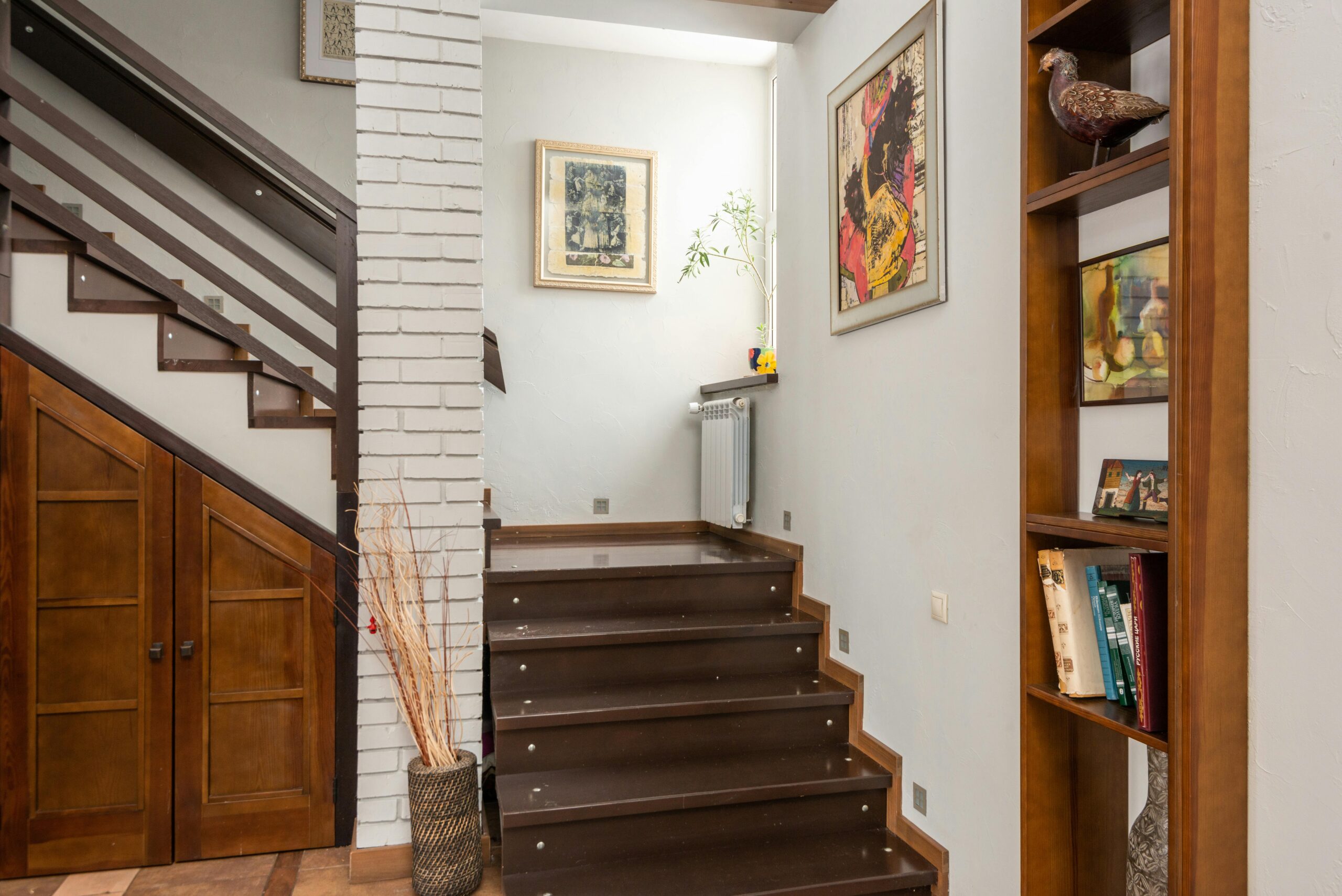 Cozy interior with a modern staircase, bookshelf, and artistic decor elements.